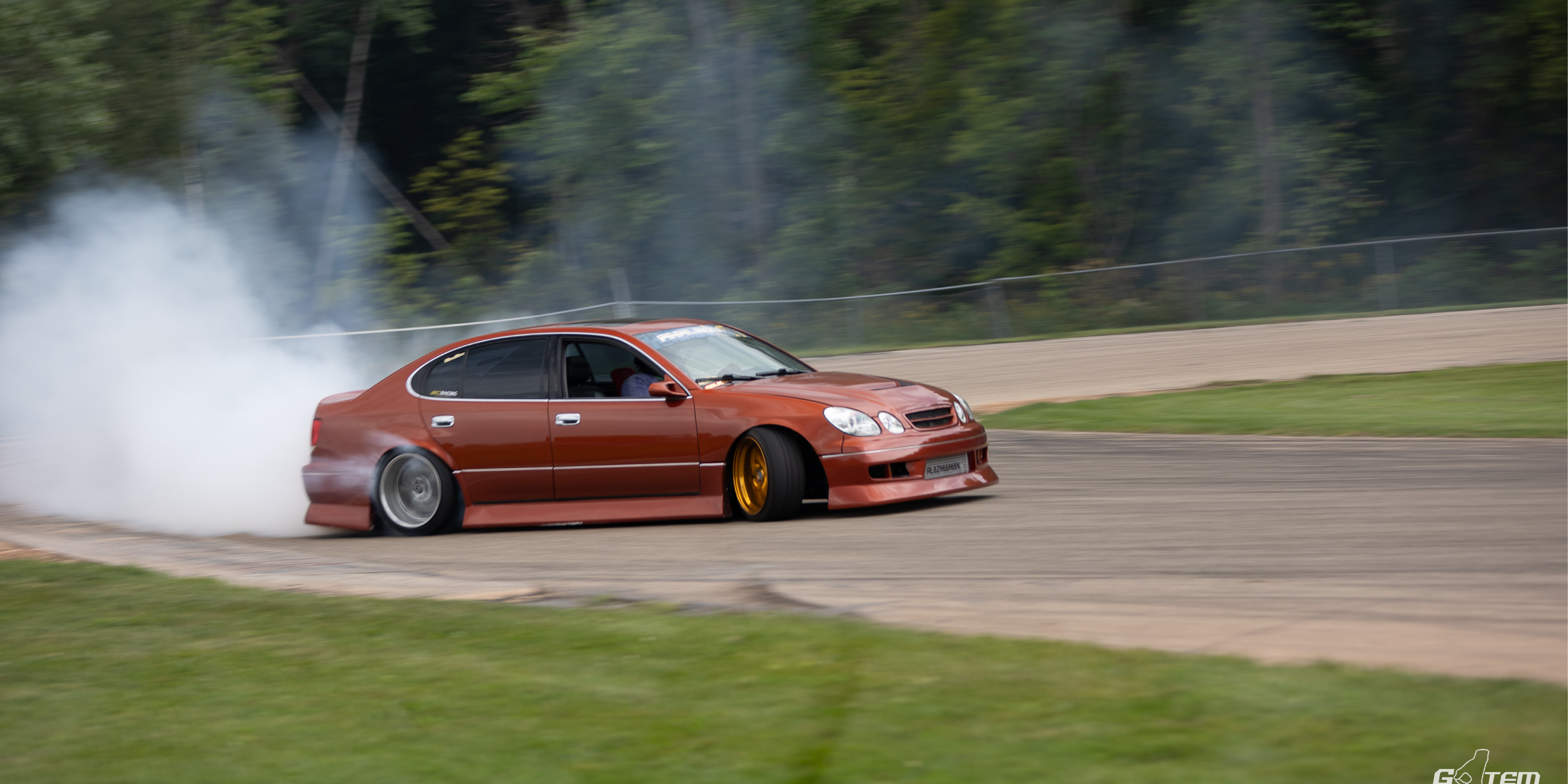 Celebrity influencer Hertrech Eugene Junior drifting a red GS300, generating heavy tire smoke on a race track.