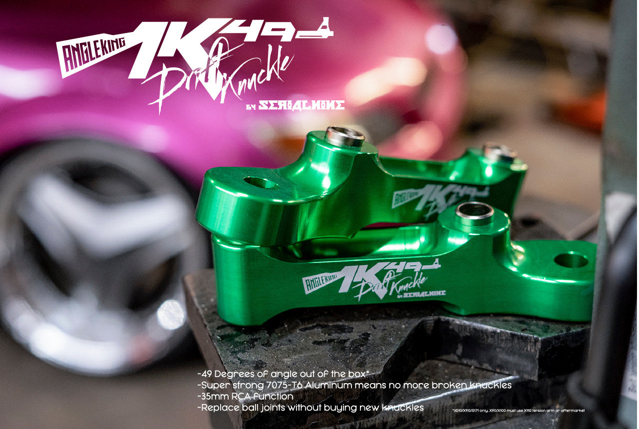 Close-up of green SERIALNINE AK49 Drift Knuckle with sleek design and laser-etched logos, against a blurred pink car.