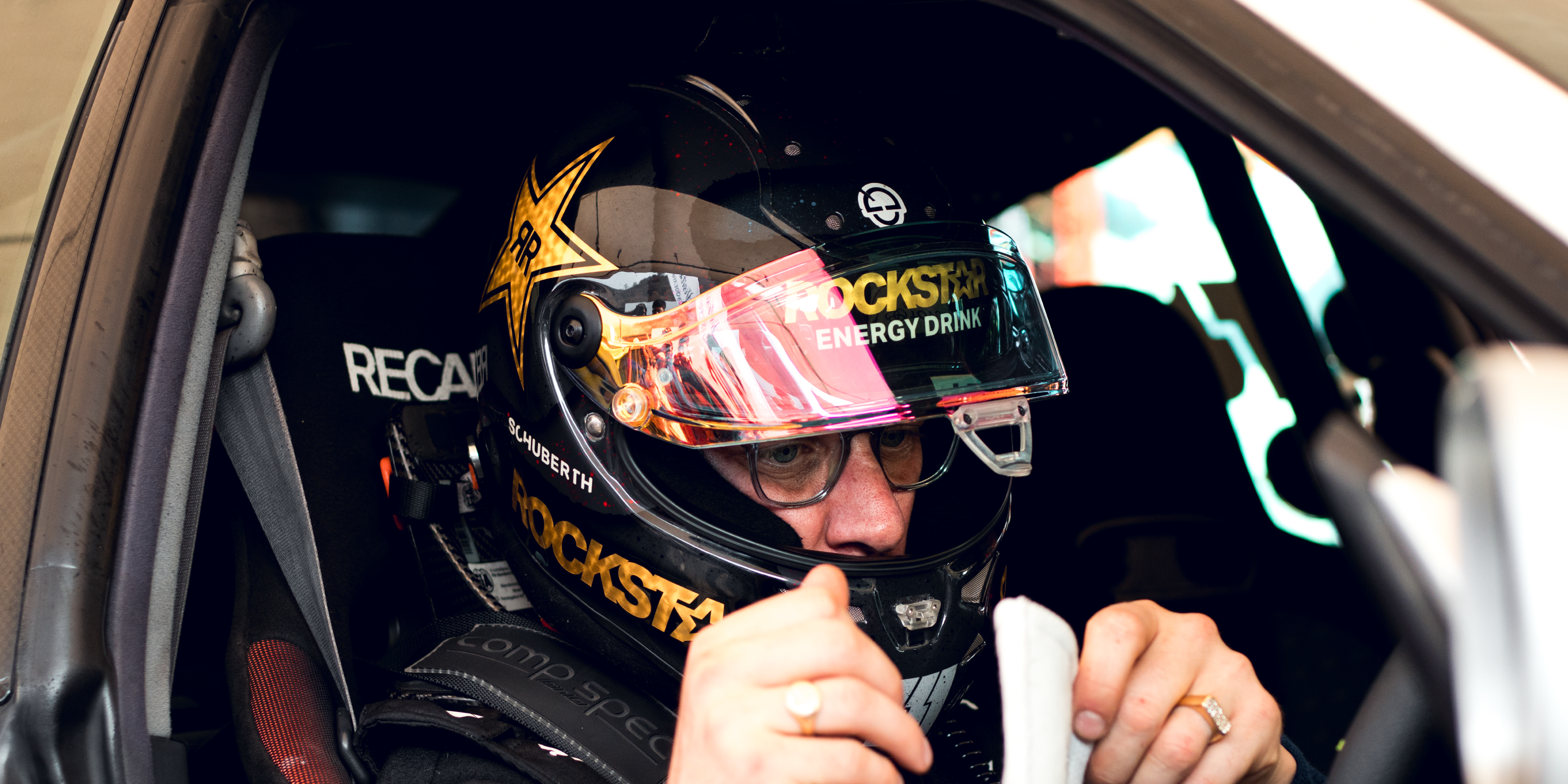 Formula D driver Ryan Tuerck in a SERIALNINE equipped Toyota Chaser, adjusting gear, wearing a Rockstar Energy Drink helmet.